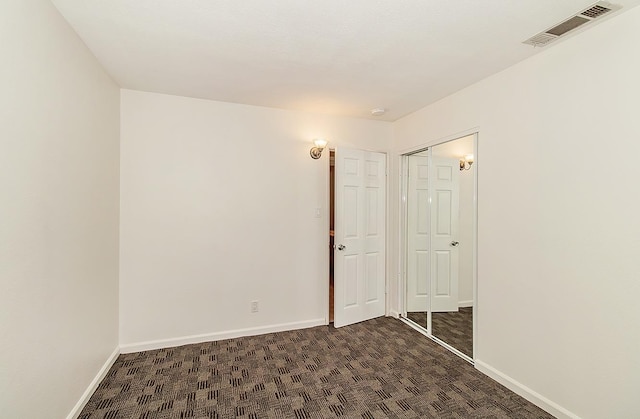 unfurnished bedroom featuring dark colored carpet and a closet