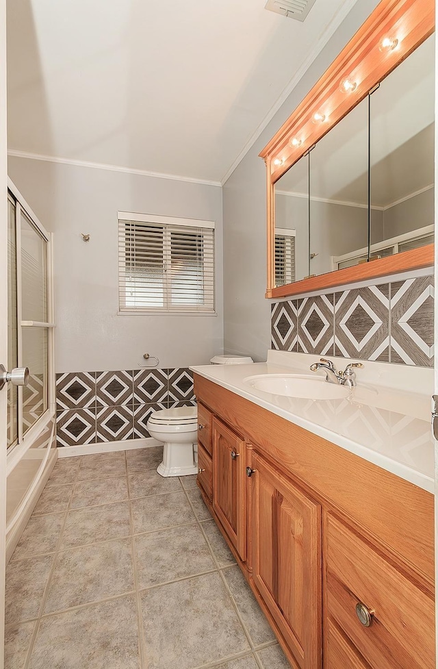 full bathroom featuring tile patterned flooring, toilet, combined bath / shower with glass door, vanity, and crown molding