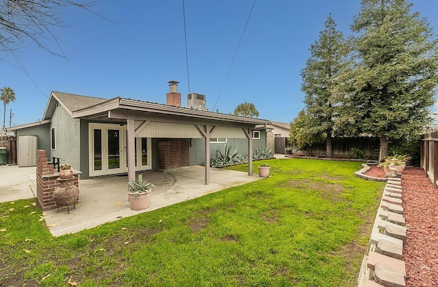 rear view of property featuring a lawn, french doors, and a patio area