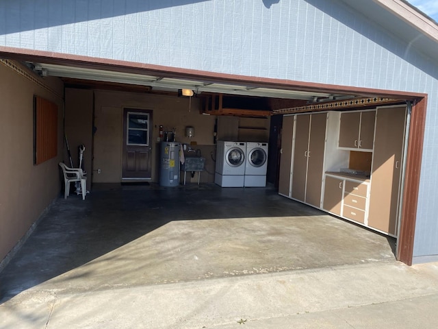 garage with electric water heater, washer and clothes dryer, and sink