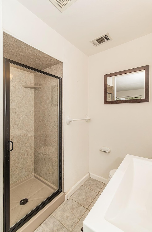 bathroom featuring tile patterned floors, toilet, and a shower with door