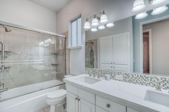 full bathroom with decorative backsplash, vanity, toilet, and shower / bath combination with glass door