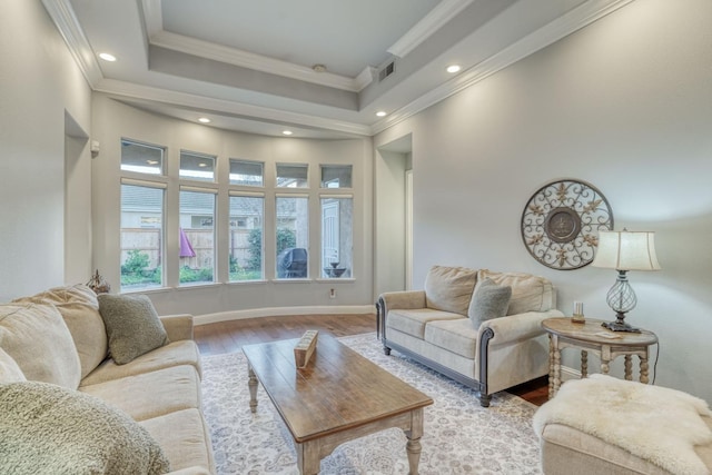 living room with hardwood / wood-style floors, a raised ceiling, and crown molding