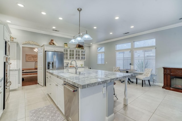 kitchen featuring sink, decorative light fixtures, a center island with sink, white cabinets, and appliances with stainless steel finishes