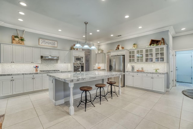 kitchen with white cabinets, an island with sink, pendant lighting, and appliances with stainless steel finishes