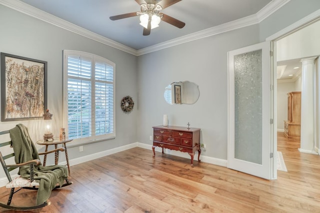 sitting room featuring ornate columns, ceiling fan, light wood-type flooring, and ornamental molding