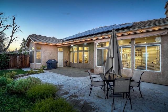 back house at dusk with a patio area and solar panels