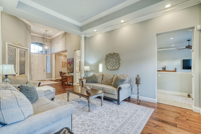 living room with ornate columns, ceiling fan, crown molding, hardwood / wood-style floors, and a tray ceiling