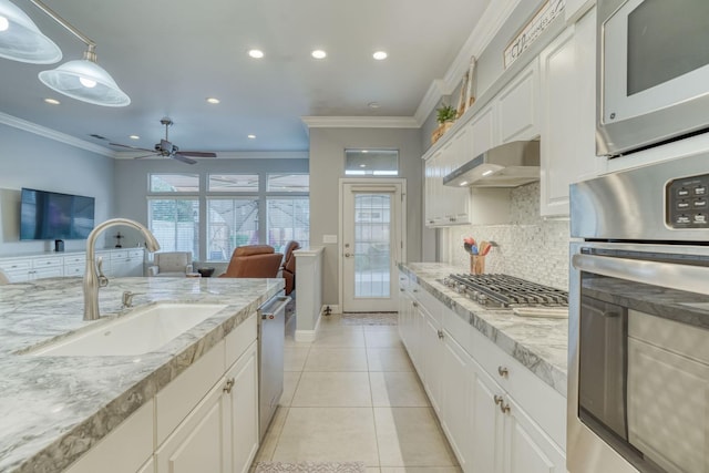 kitchen with sink, decorative backsplash, appliances with stainless steel finishes, range hood, and white cabinetry