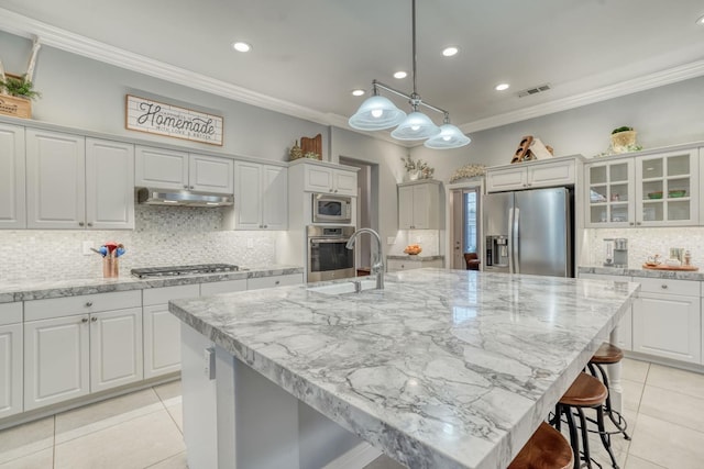 kitchen featuring a large island, sink, stainless steel appliances, and decorative light fixtures