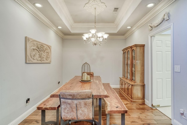 dining room featuring a chandelier, ornamental molding, a tray ceiling, and light hardwood / wood-style floors