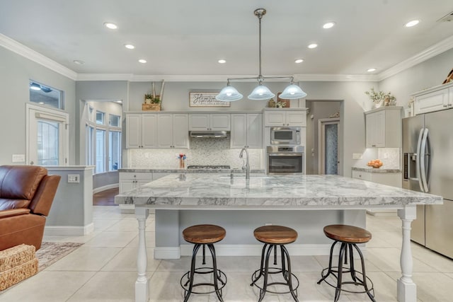 kitchen with sink, hanging light fixtures, a spacious island, appliances with stainless steel finishes, and ornamental molding