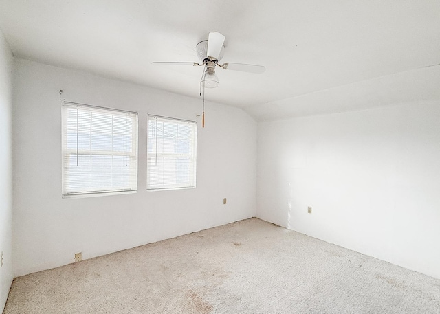 empty room with carpet flooring, vaulted ceiling, and ceiling fan