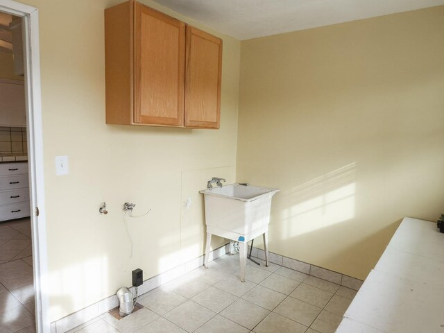 clothes washing area featuring light tile patterned floors and cabinets