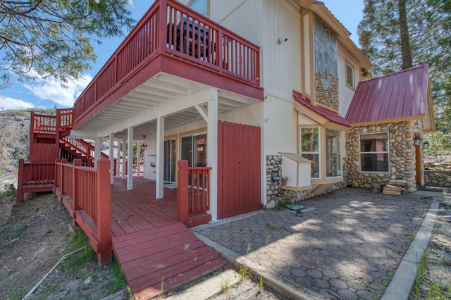 39722 Crest Point Ln, Shaver Lake, CA 93664 - rear view of property featuring stone siding, a wooden deck, a patio area, and metal roof