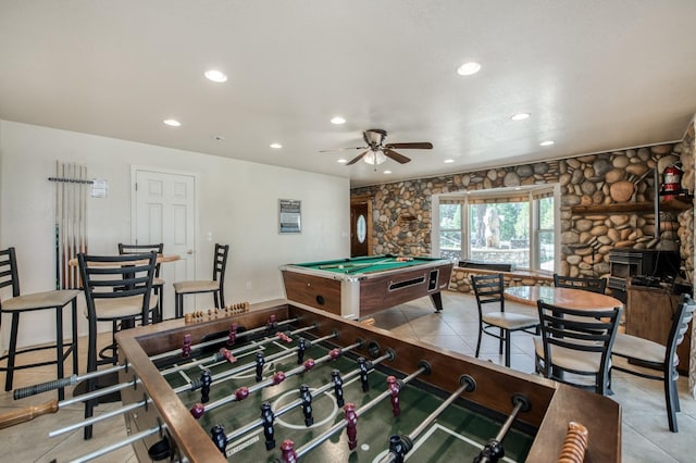 game room with ceiling fan, light tile patterned floors, pool table, and a wood stove