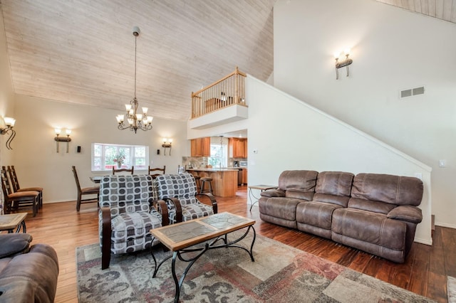 living room with hardwood / wood-style floors, high vaulted ceiling, and a chandelier