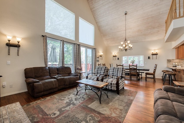 living room with hardwood / wood-style floors, a wealth of natural light, high vaulted ceiling, and an inviting chandelier