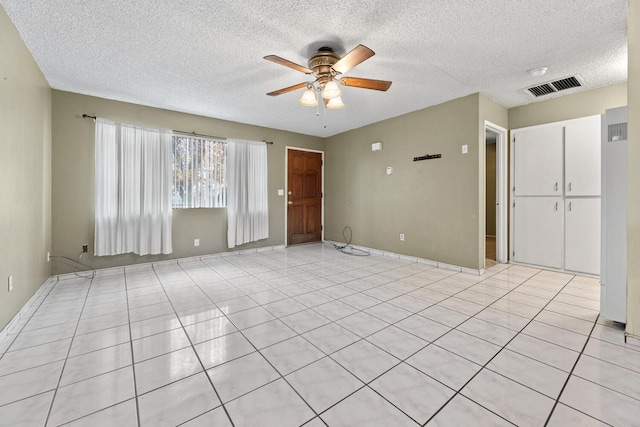 unfurnished room with ceiling fan, a textured ceiling, and light tile patterned floors