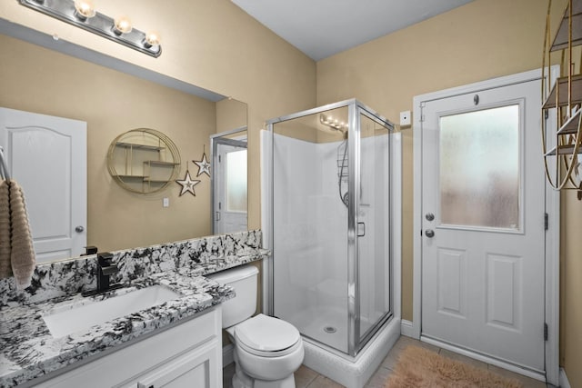 bathroom featuring tile patterned flooring, vanity, toilet, and an enclosed shower