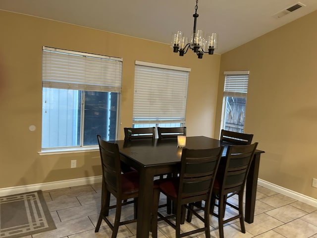 dining area featuring a chandelier, vaulted ceiling, a healthy amount of sunlight, and light tile patterned flooring