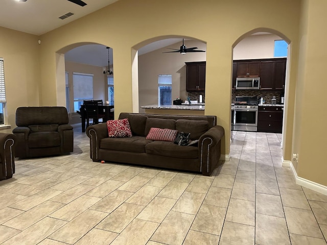 living room with lofted ceiling, ceiling fan, and light tile patterned floors