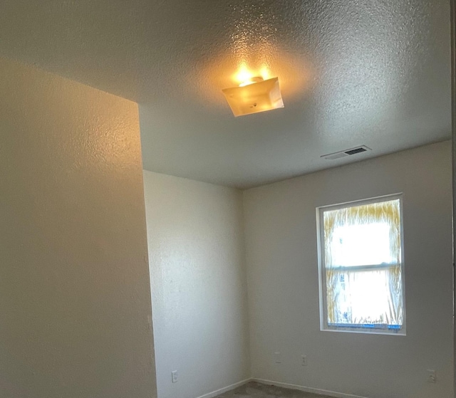 unfurnished room with visible vents and a textured ceiling