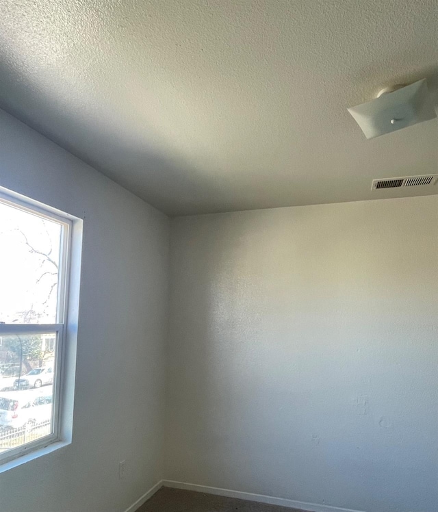 unfurnished room with visible vents and a textured ceiling