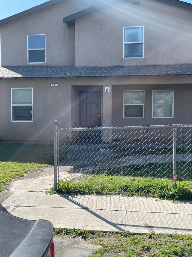 townhome / multi-family property with a fenced front yard and stucco siding