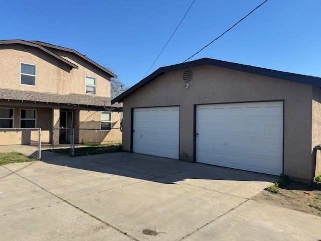 view of front of home featuring a garage, fence, an outdoor structure, and stucco siding