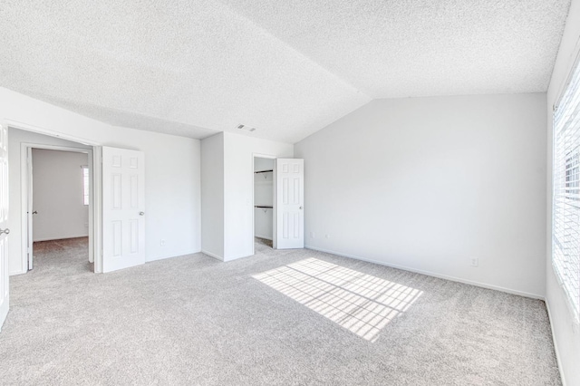 unfurnished bedroom with light colored carpet, lofted ceiling, multiple windows, and a closet