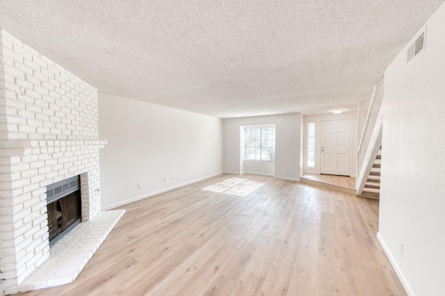 unfurnished living room featuring a textured ceiling, a fireplace, and light hardwood / wood-style flooring