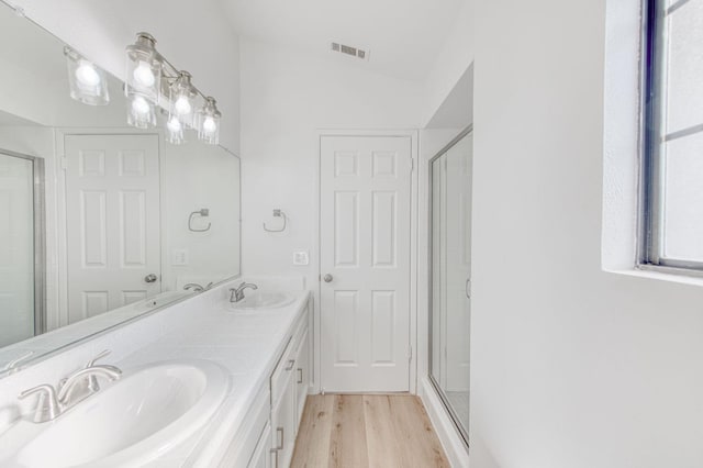 bathroom featuring wood-type flooring, vanity, vaulted ceiling, and a shower with shower door