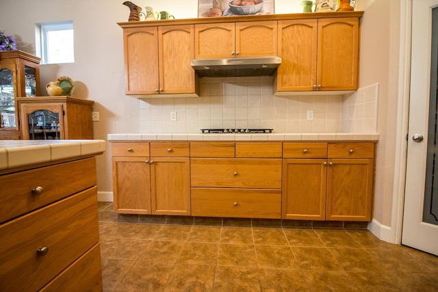 kitchen featuring tile countertops, tile patterned flooring, gas stovetop, and backsplash