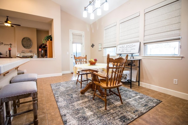 dining space with ceiling fan, light tile patterned floors, and vaulted ceiling