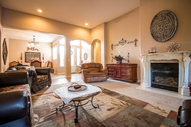 carpeted living room featuring a notable chandelier and a high end fireplace