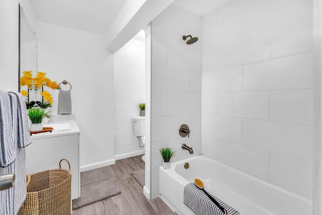 full bathroom featuring hardwood / wood-style flooring, vanity, tiled shower / bath combo, and toilet