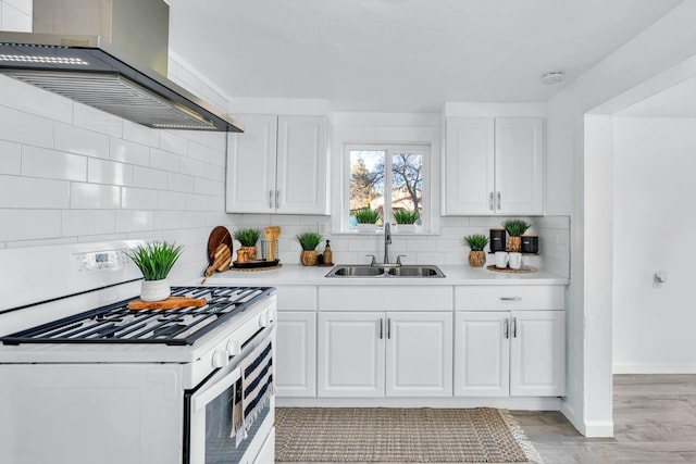 kitchen with white cabinets, gas stove, wall chimney exhaust hood, and sink