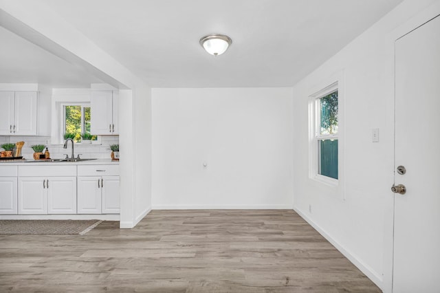 unfurnished dining area with a healthy amount of sunlight, sink, and light hardwood / wood-style floors