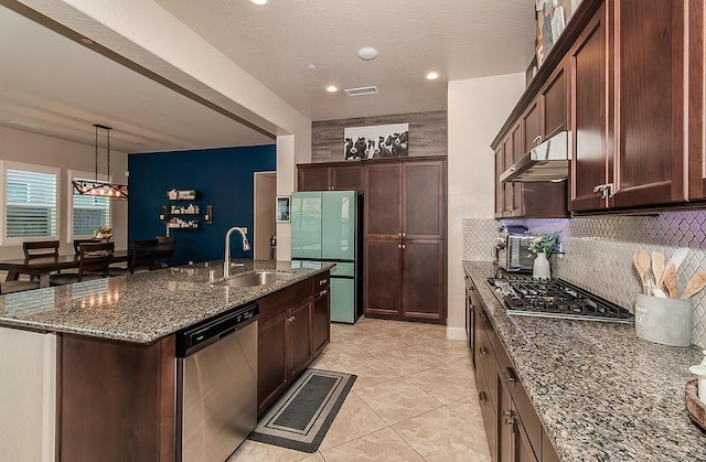 kitchen with sink, stainless steel appliances, tasteful backsplash, dark stone counters, and a kitchen island with sink