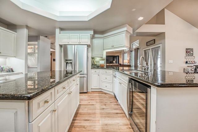 kitchen featuring a kitchen island with sink, stainless steel fridge, sink, and beverage cooler