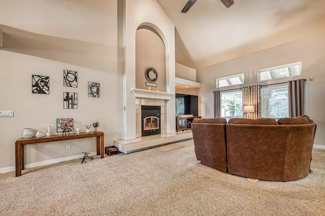 carpeted living room with ceiling fan, a fireplace, and high vaulted ceiling