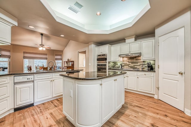 kitchen with a kitchen island, dark stone countertops, white cabinetry, and kitchen peninsula