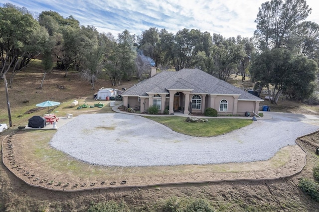 single story home featuring a storage unit and a front lawn