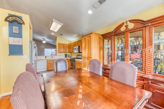 dining space with light hardwood / wood-style flooring, lofted ceiling, and sink