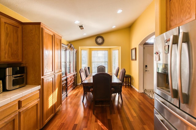 dining space featuring dark hardwood / wood-style flooring and vaulted ceiling