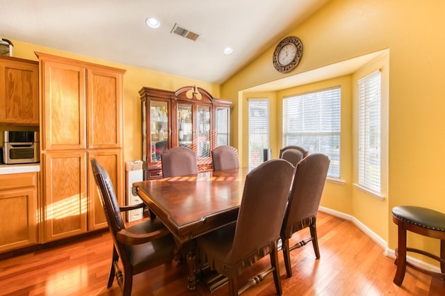 dining room featuring light wood-type flooring and lofted ceiling