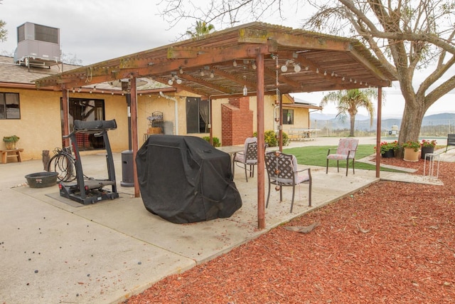 view of patio with a mountain view, central AC, area for grilling, and a pergola