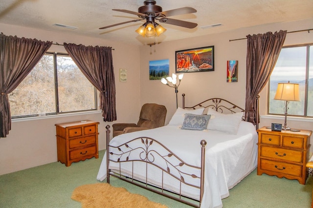 bedroom featuring ceiling fan, light carpet, and a textured ceiling