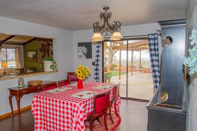 dining room featuring a healthy amount of sunlight, a textured ceiling, a chandelier, and concrete flooring